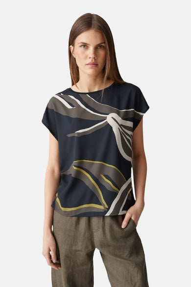 Blauw blouse met korte mouwen van OPUS, met abstracte print en gecombineerd met een olijfgroene broek.
