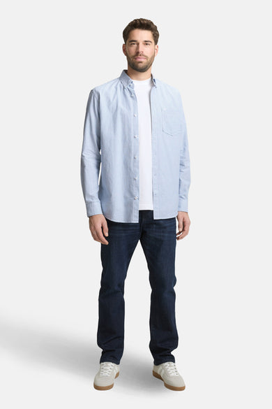 Blauw overhemd met lange mouwen van TOM TAILOR, met een gestreept patroon en een borstzak, gedragen over een wit T-shirt met donkere jeans en sneakers.
