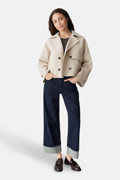 Manteau ecru court d'OPUS, avec des manches longues et une fermeture à double bouton, associé à un pantalon foncé et des chaussures.