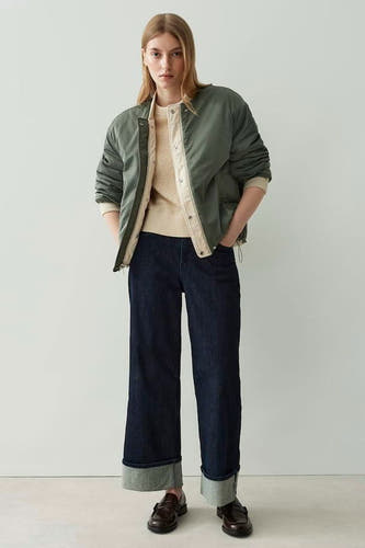 Mauve court manteau d'OPUS, avec un motif de visage rembourré, des manches longues et des jeans foncés.