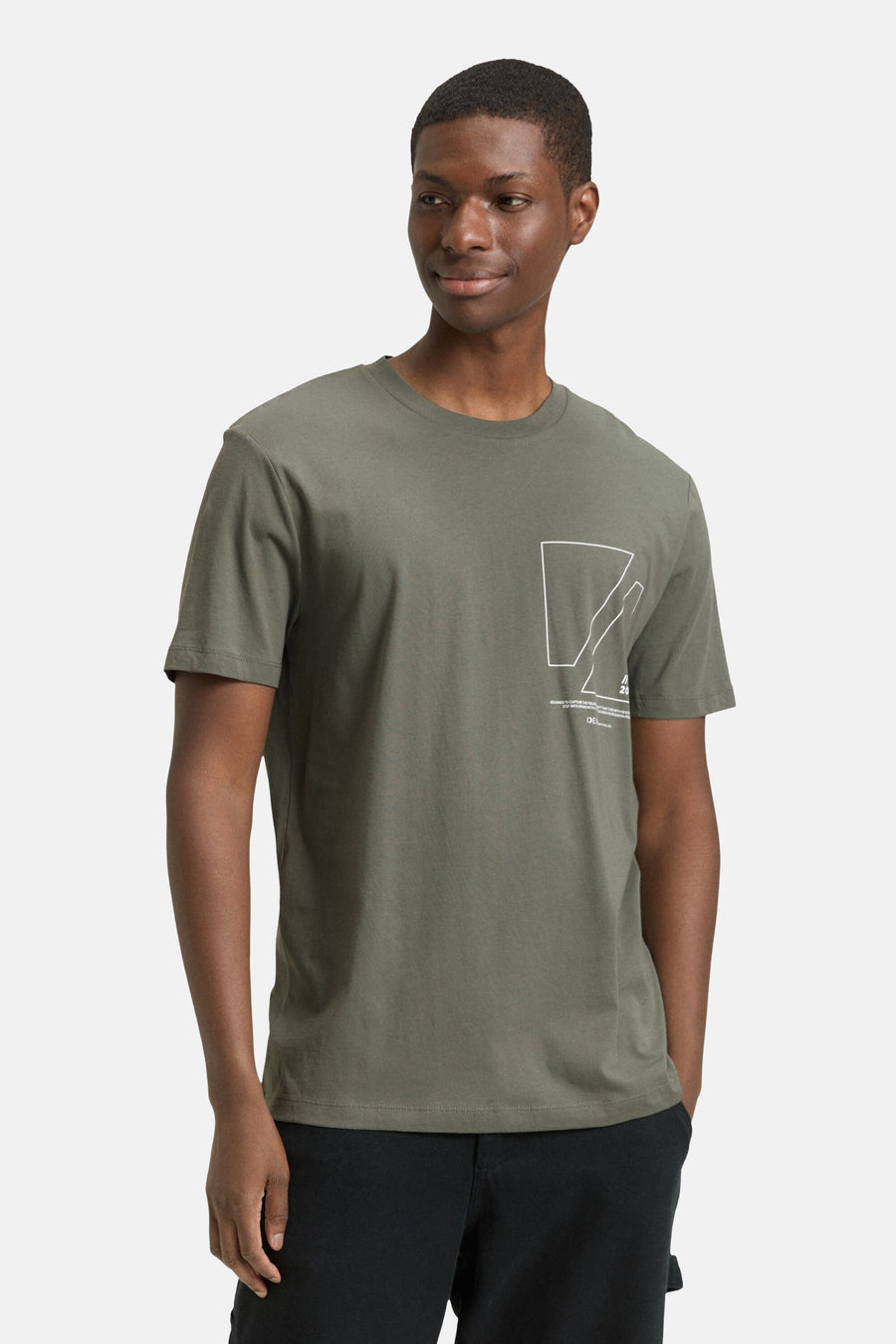 T-shirt vert de mantes courtes man TOM TOM TOMOR, im un graphique, associé à une pantalon noir et des baskets blanches.