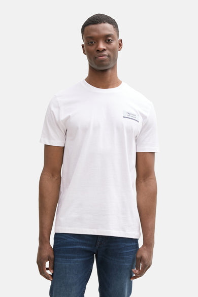 T-shirt blanc à manches courtes de TOM TAILOR, avec un petit logo sur la poitrine et porté avec un jean bleu.