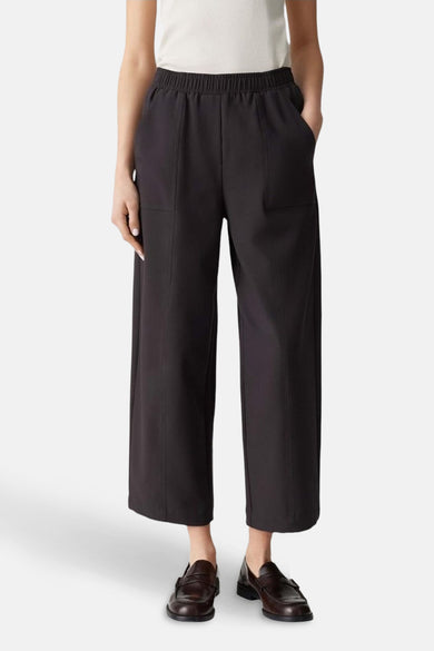 Pantalon brun d'OPUS, avec des jambes larges, des poches et une ceinture élastique, porté avec des chaussures brunes.