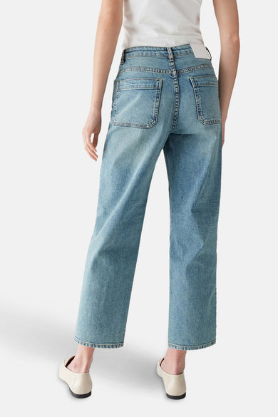 Lichtblauwe denim mom jeans van OPUS, gezien van achteren, met zakken en ecrukleurige schoenen.
