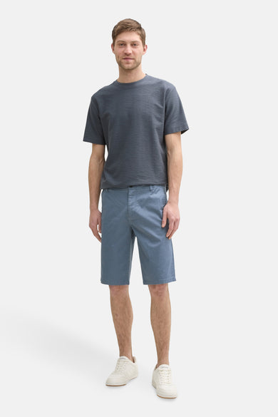 Blauwe short van TOM TAILOR, gecombineerd met een grijs T-shirt en witte sneakers.