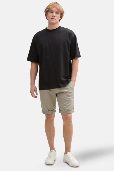 Shorts kaki de TOM TAILOR, avec des poches rabattues, associés à un t-shirt noir et des baskets blanches.