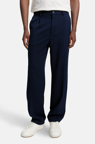 Pantalon bleu de TOM TAILOR, avec plis et une large ceche, associé à des baskets blanches.