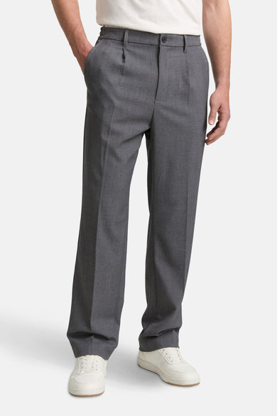 Grijze broek van TOM TAILOR, met plooien en steekzakken, gedragen met witte sneakers.