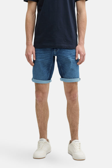 Jeansshort van midblauw denim van TOM TAILOR, met opgerolde pijpen en witte sneakers.