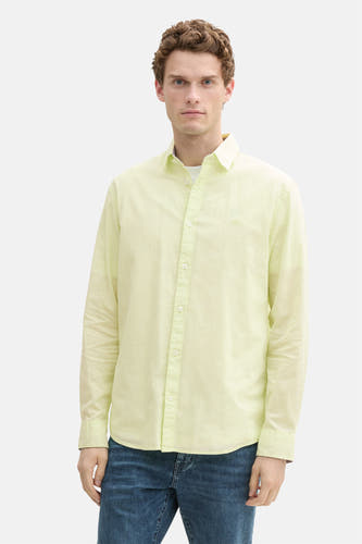 Chemise verte à manches longues de TOM TAILOR, portée sur un t-shirt blanc et des jeans bleus, avec des chaussures sombres.