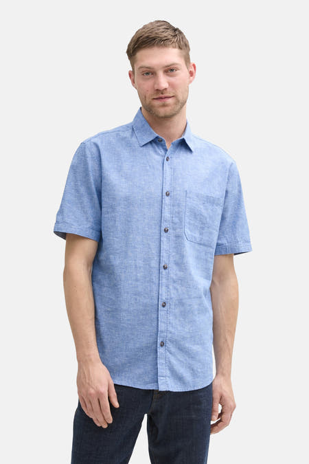 Chemise bleue à manches courtes de TOM TAILOR, avec col boutonné et poche poitrine, portée avec un jeans foncé.