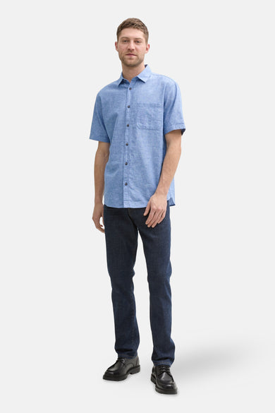 Blauw overhemd met korte mouwen van TOM TAILOR, met knoopsluiting en borstzak, gecombineerd met donkere jeans en zwarte schoenen.