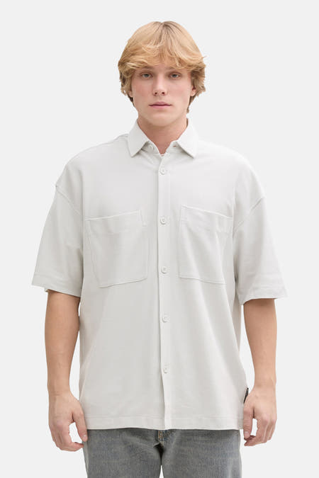 Chemise grise à manches courtes de TOM TAILOR, portée avec un t-shirt blanc, un jean gris et des baskets blanches.