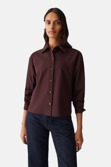 Vrouw in bordeauxrode blouse en spijkerbroek.