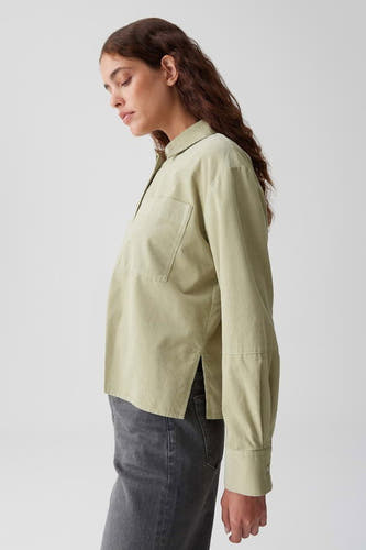 Groene blouse met lange mouwen van OPUS, met een borstzak en zijsplitjes, gedragen met grijze jeans, in zijaanzicht.
