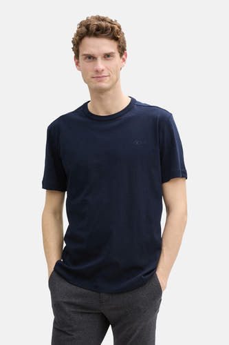 Donkerblauw T-shirt met korte mouwen van TOM TAILOR, met een klein logo en gedragen met een grijze broek.
