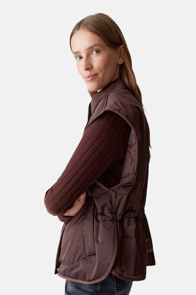 Rode bodywarmer van OPUS, met koord in de taille, gedragen over een bruine top.