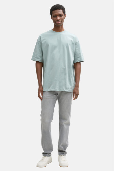 Grijze slim jeans de TOM TAILOR, gecombineerd met een lichtblauw T-shirt en witte sneakers.