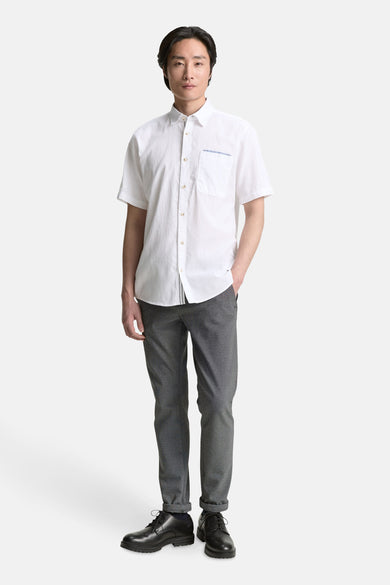 Chemise blanche à manches courtes de TOM TAILOR, avec poche poitrine, associée à un pantalon gris et des chaussures noires.