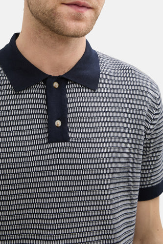 Close-up poloshirt met donkerblauwe kraag en knopen.