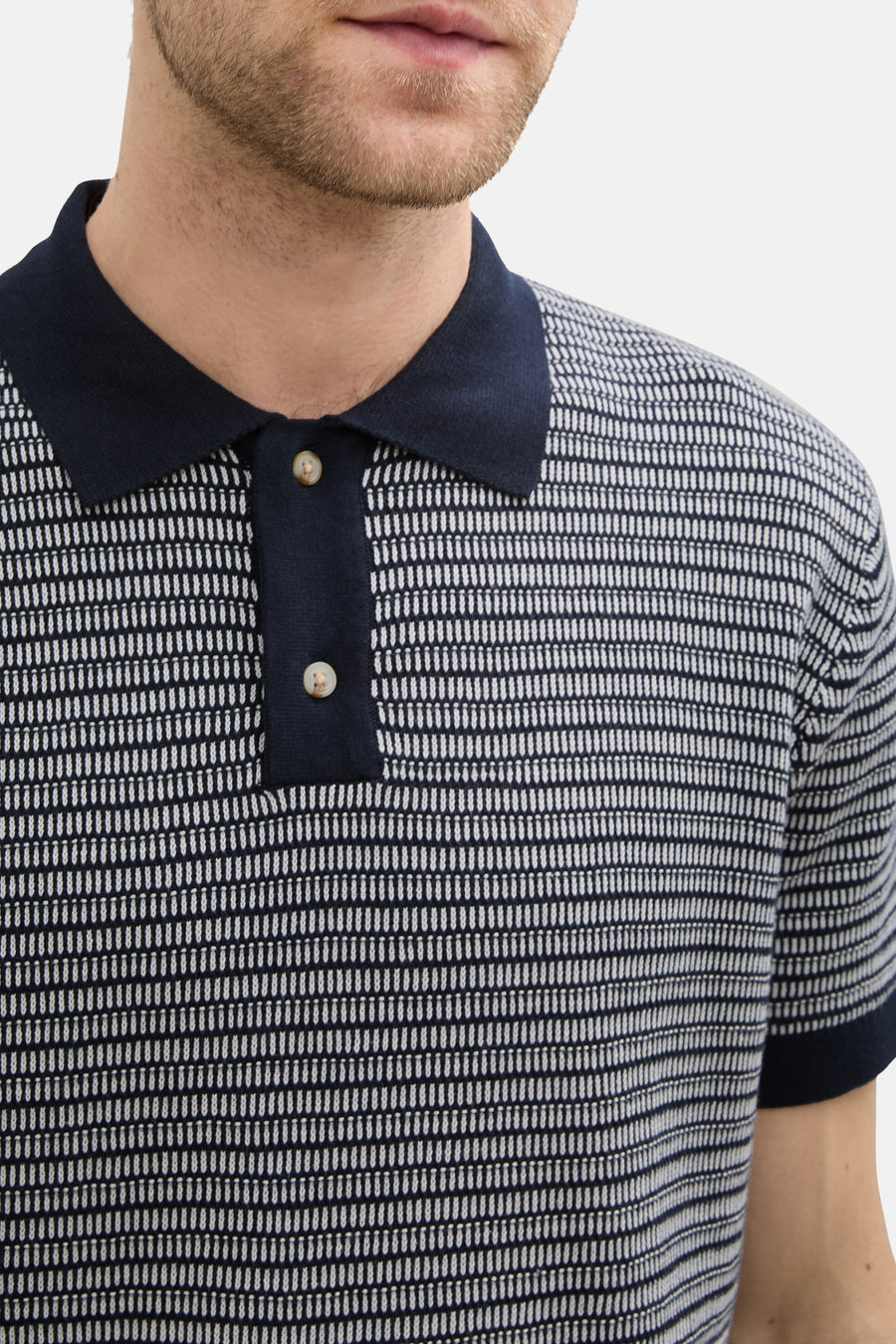 Close-up poloshirt met donkerblauwe kraag en knopen.