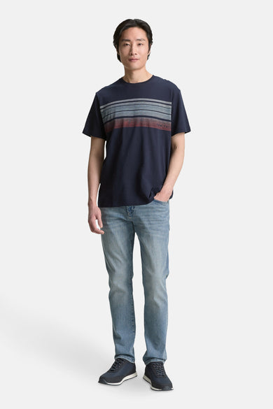 T-shirt bleu à manches courtes de TOM TAILOR, avec des rayures horizontales sur la poitrine, associé à des jeans et des chaussures bleues.