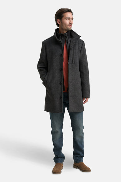 Grijze lange jas van TOM TAILOR, met een rode trui en jeans, en bruine schoenen.