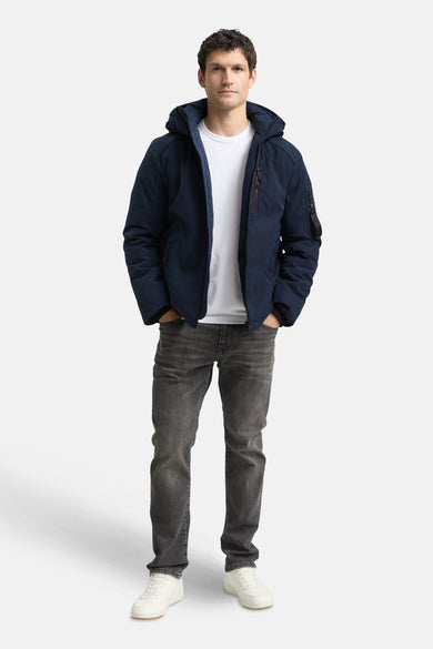 Manteau court bleu de TOM TAILOR, avec capuche et jeans gris avec des chaussures blanches.