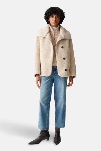 Beige korte jas van OPUS, met donkere knopen, gecombineerd met jeans en zwarte laarsjes.
