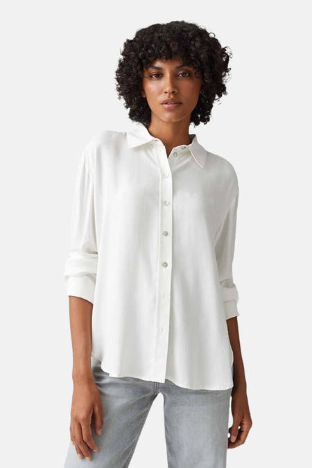 Chemise blanche à manches longues d'OPUS, portée avec un jean gris et une main dans la poche.