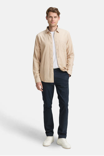 Chemise beige à longues manches de TOM TAILOR, portée sur un t-shirt blanc et des pantalons bleu marine, avec des baskets blanches.
