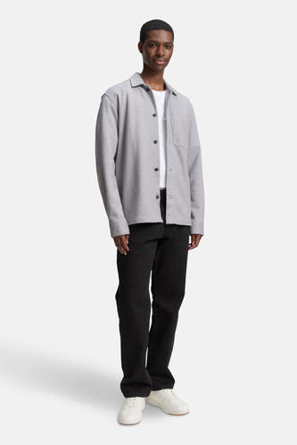 Grijs hemd van TOM TAILOR, met knoopsluiting, borstzak en gedragen over een wit T-shirt met zwarte jeans.