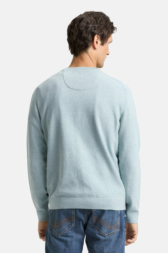 Achterkant van een man in een lichtblauwe trui en blauwe jeans.