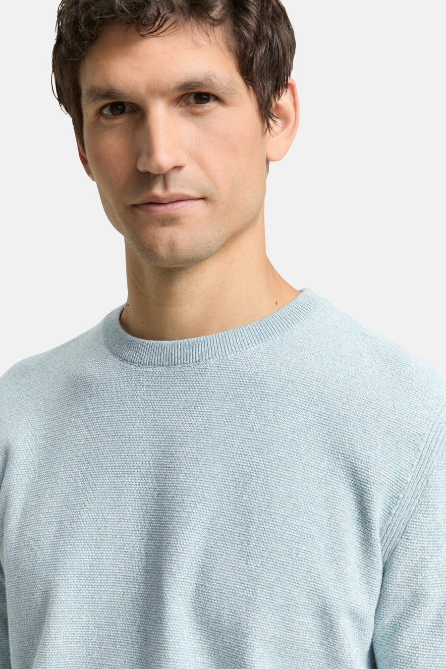 Mannelijk model draagt lichtblauwe trui.