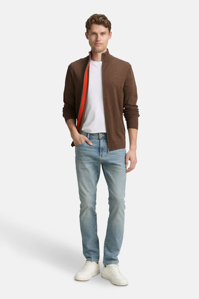 Bruin gilet van TOM TAILOR, gedragen over een wit T-shirt en een blauwe jeans, met witte sneakers.
