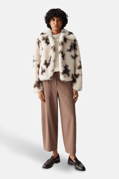Beige korte jas van OPUS, met donkerbruine vlekken en gedragen met bruine pantalon en loafers.