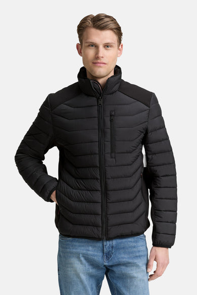 Zwarte korte jas van Tom Tailor, met rits en details van gewatteerd patroon, gedragen over een blauwe jeans.