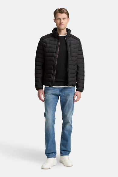 Zwarte korte jas van Tom Tailor, met stiksels, gedragen met jeans en witte sneakers.