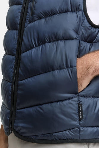 Gilet bleu de TOM TAILOR, avec poche sur le côté et main visible.