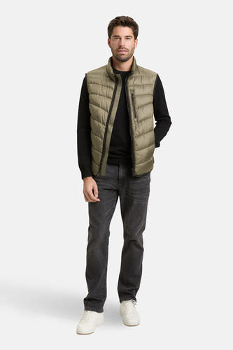 Kaki bodywarmer van TOM TAILOR, gedragen over een zwarte trui en grijze jeans met witte sneakers.