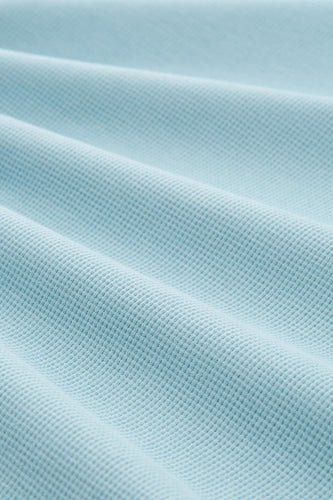 Lichtblauw wafelkatoen met plooien.
