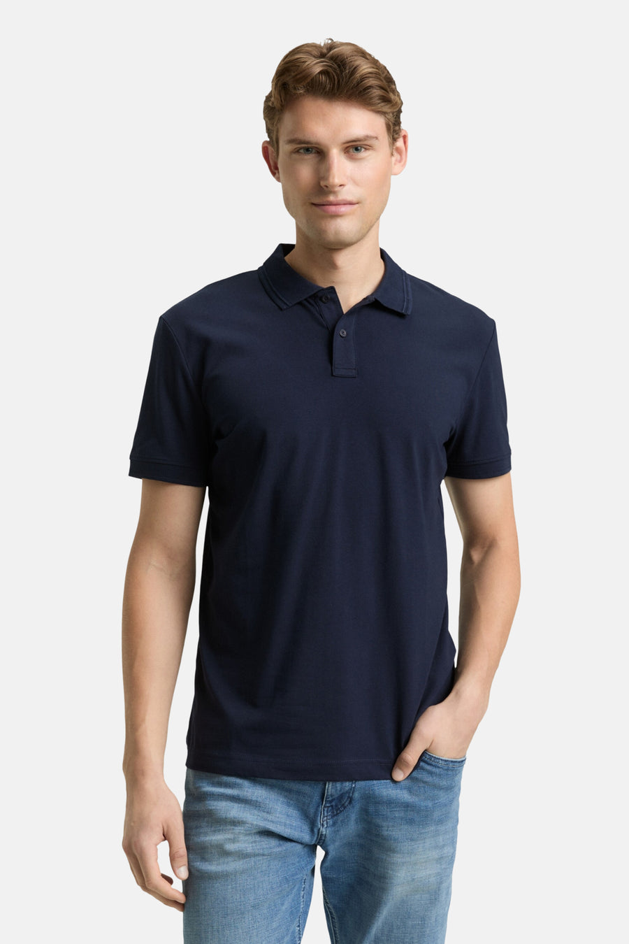Man met een donkerblauw poloshirt en blauwe jeans.
