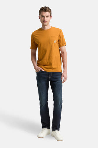 Geel T-shirt met korte mouwen van TOM TAILOR, met borstzakje en een man in donkere jeans en witte sneakers.