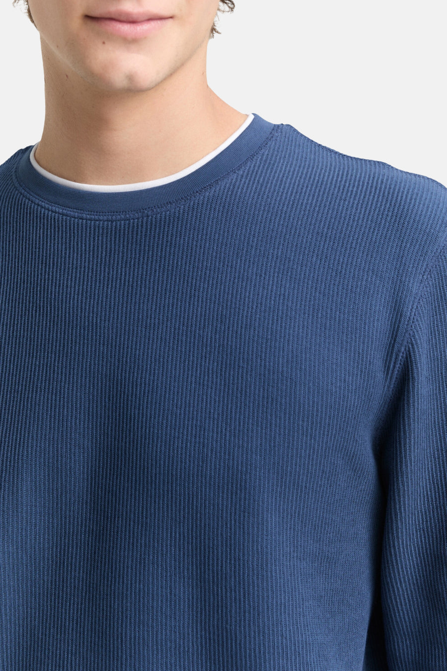 Blauw geribbelde trui met witte kraag.
