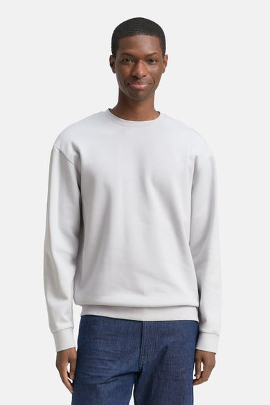 Pull gris à col rond de TOM TAILOR, porté avec un jean bleu foncé.