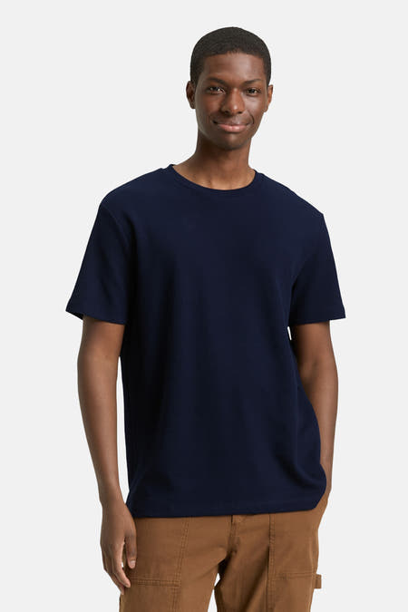 T-shirt bleu à manches courtes de TOM TAILOR, porté avec un pantalon marron et des baskets blanches.