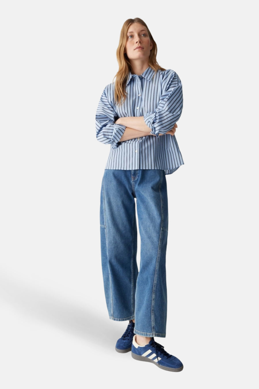 Blauw gestreept overhemd met lange mouwen van OPUS, met gekruiste armen en gecombineerd met jeans en blauwe sneakers.
