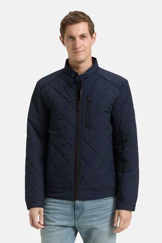 Korte blauwe jas van TOM TAILOR, met een ruitjespatroon en een ritssluiting, gedragen met een lichtblauwe spijkerbroek.
