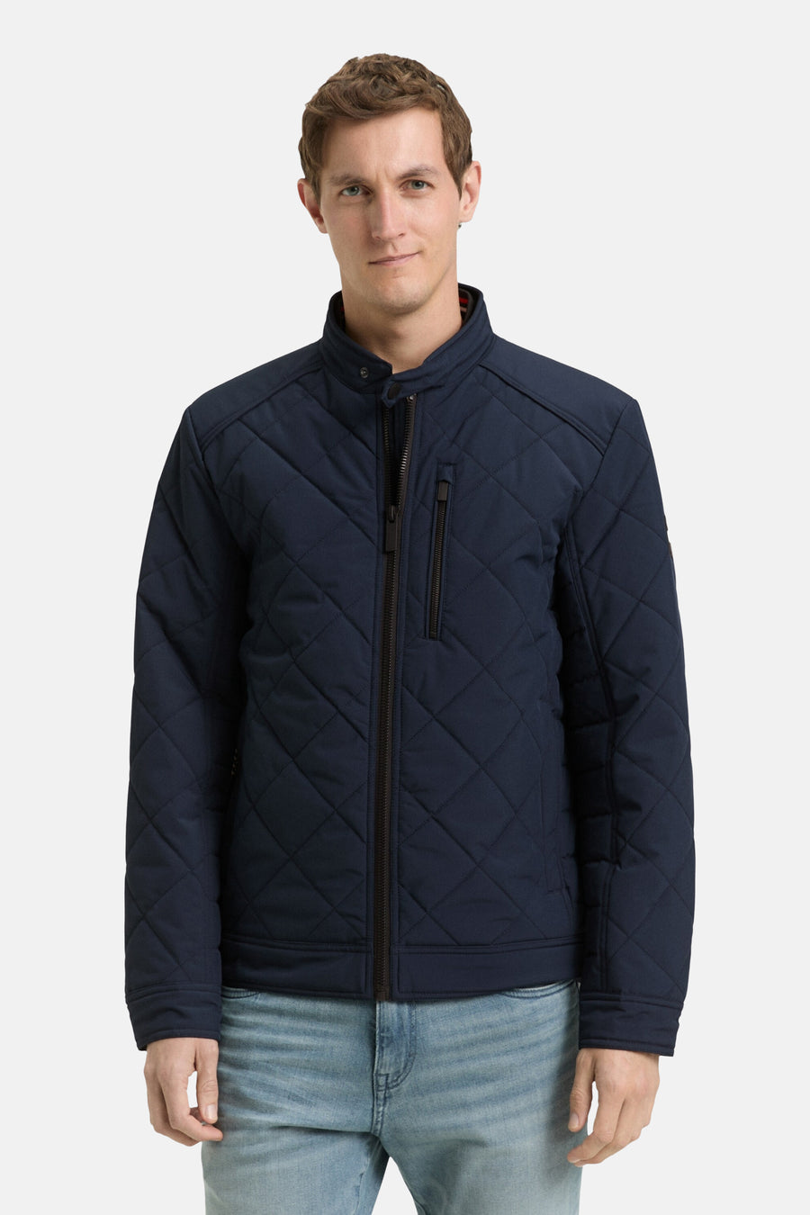 Korte blauwe jas van TOM TAILOR, met een ruitjespatroon en een ritssluiting, gedragen met een lichtblauwe spijkerbroek.
