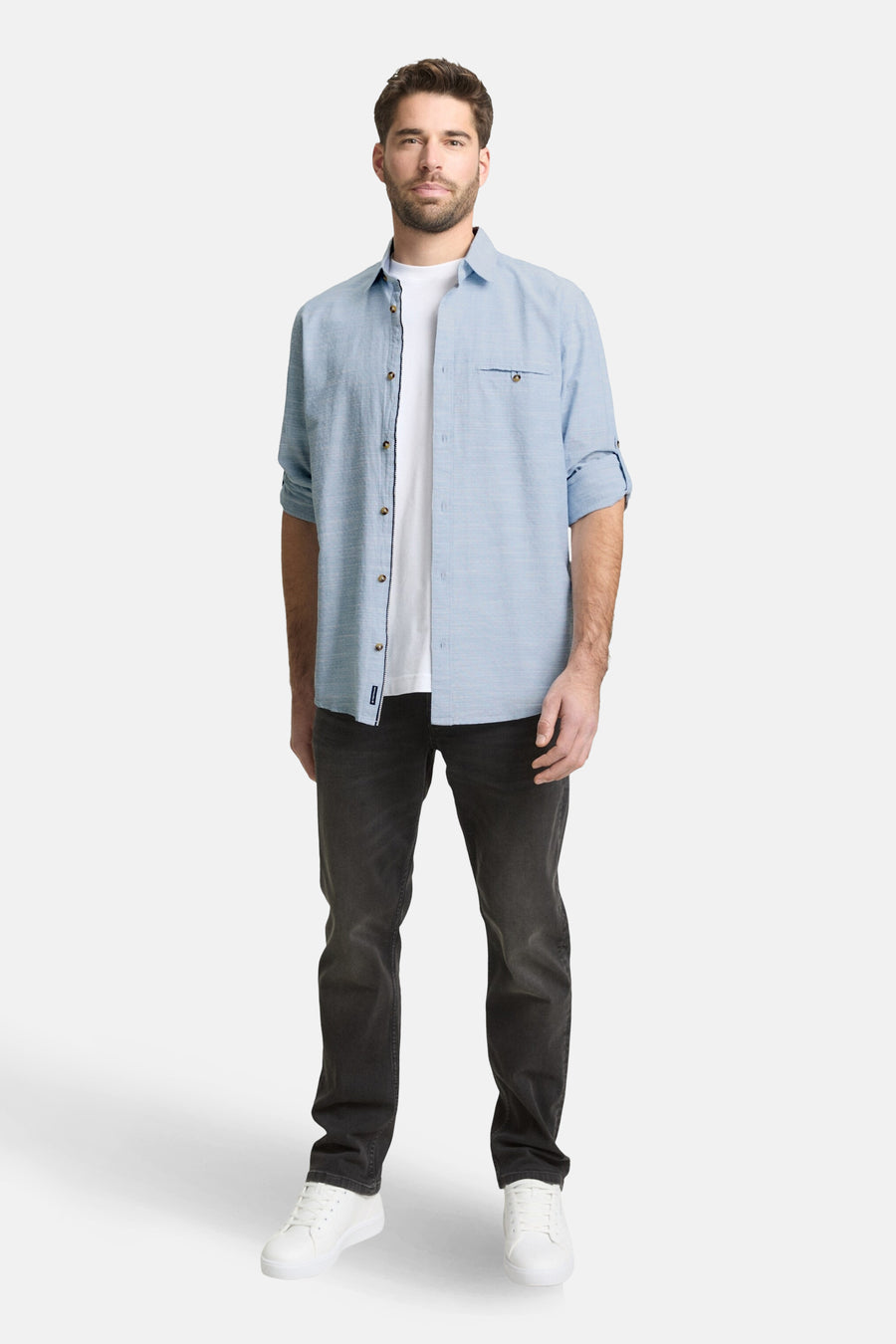 Blauw overhemd met lange mouwen van TOM TAILOR, met een borstzak en gedragen over een wit T-shirt, gecombineerd met een donkere jeans en witte sneakers.